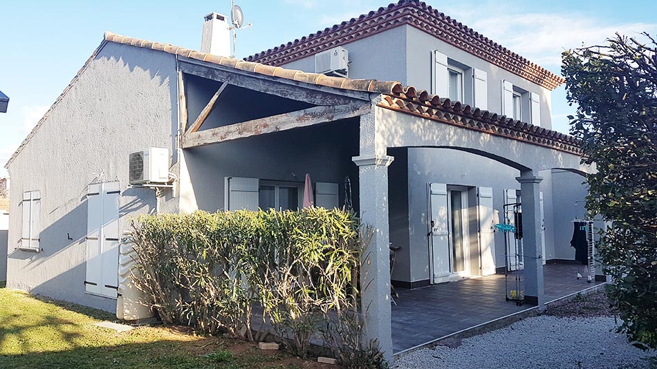 Maison blanche avec volets bleus et terrasse