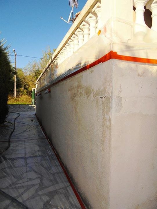 Mur blanc avec bordure orange, tuyau au sol, structure en béton