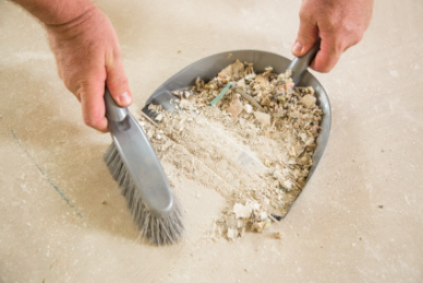 Personne brosse des débris dans une pelle