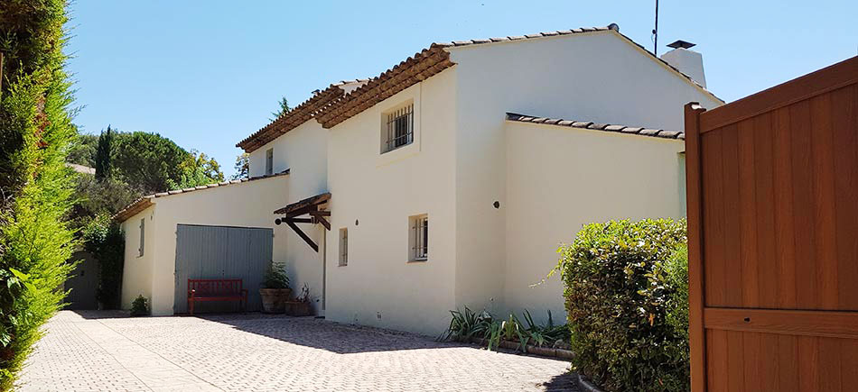 Maison blanche avec toit en tuiles, garage et clôture en bois