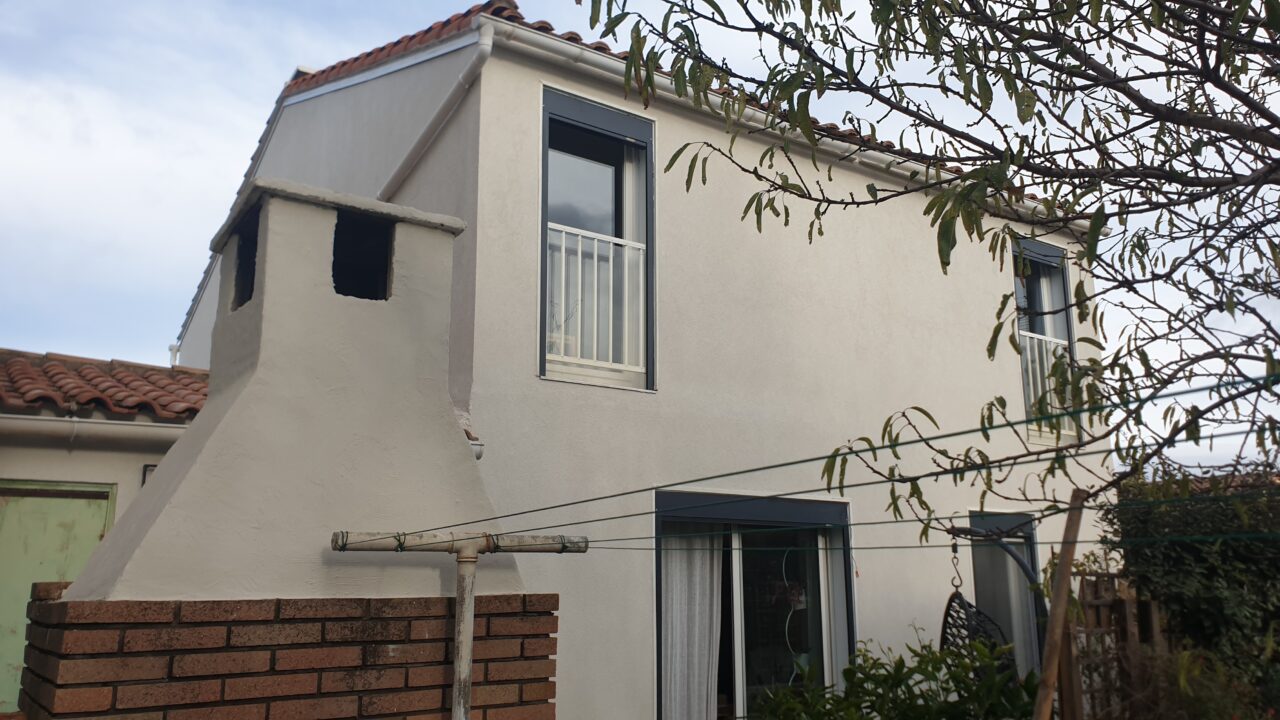 Façade d'une maison à étage avec fenêtres et toit en tuiles