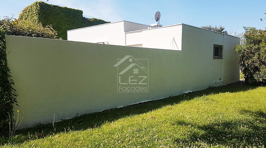 Maison blanche avec mur vert et antenne