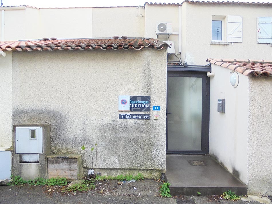 Bâtiment avec enseigne AUDITION, porte et boîte aux lettres