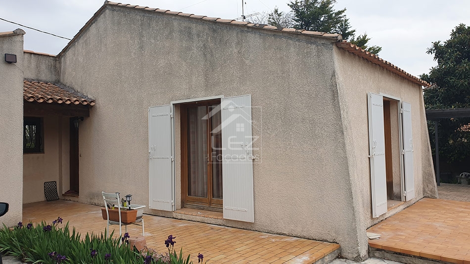 Maison en stuc avec terrasse en bois et volets blancs