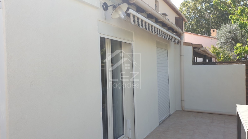 Terrasse extérieure avec portes vitrées et stores