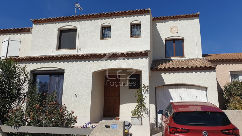 Maison à deux étages avec voiture rouge devant
