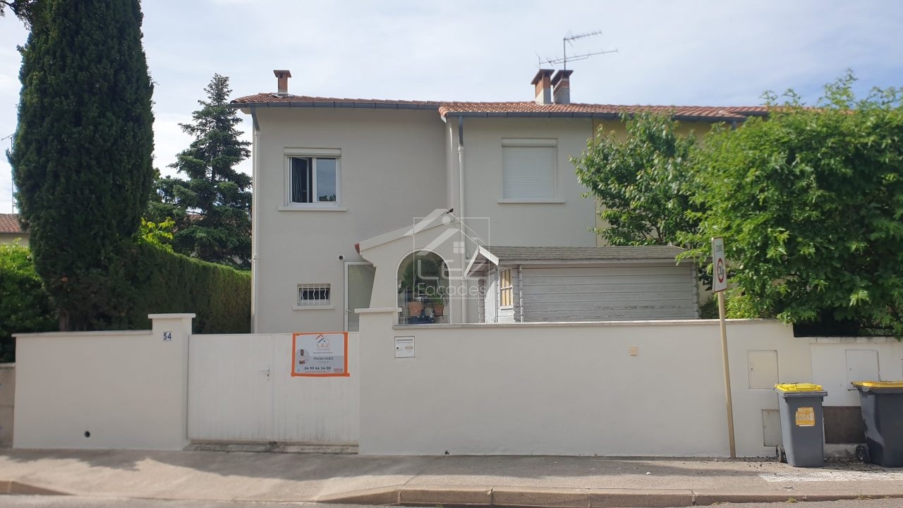 Maison blanche avec clôture et poubelles